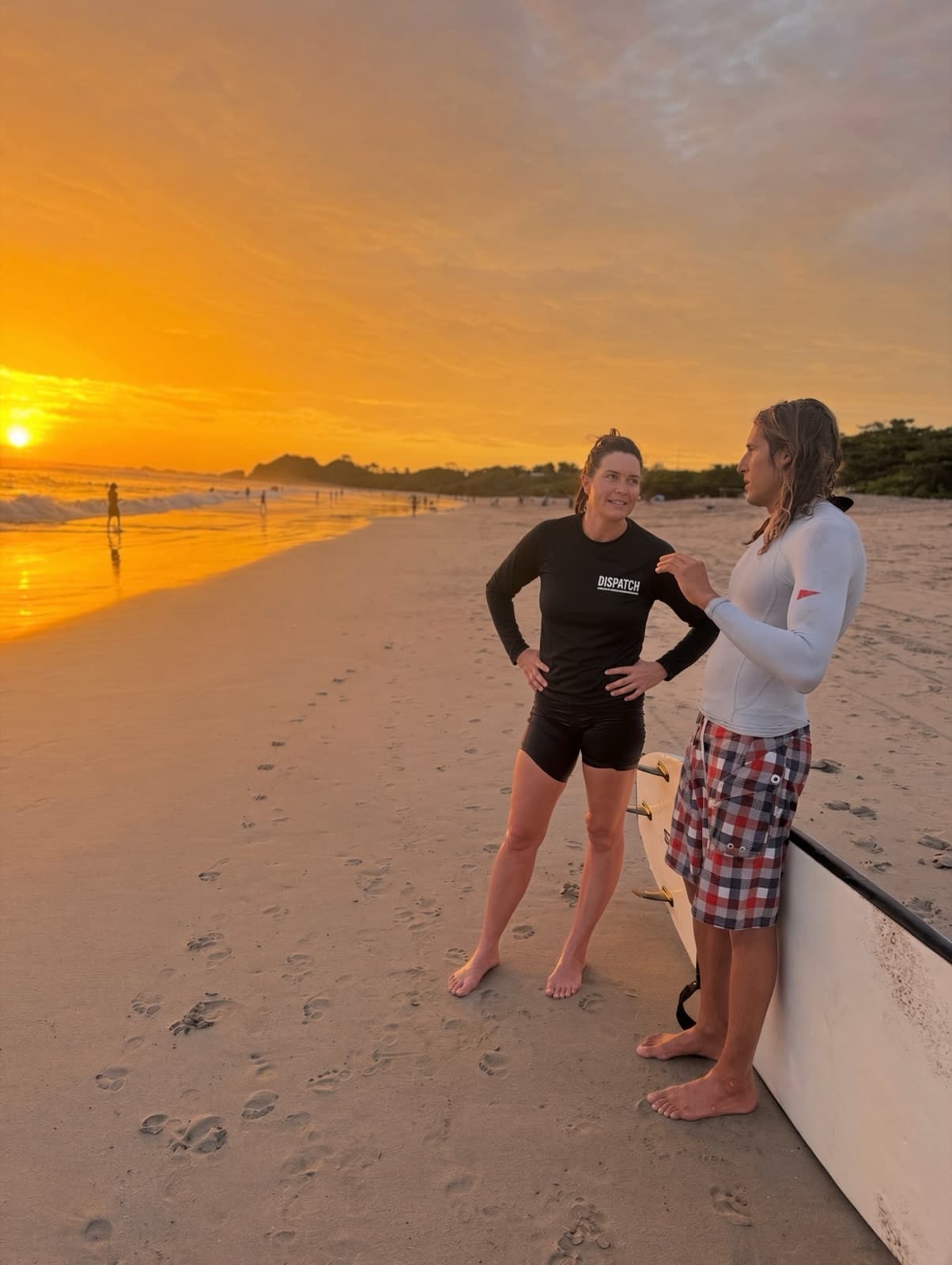 Two surfers talking on Playa Guiones, Nosara, at sunset